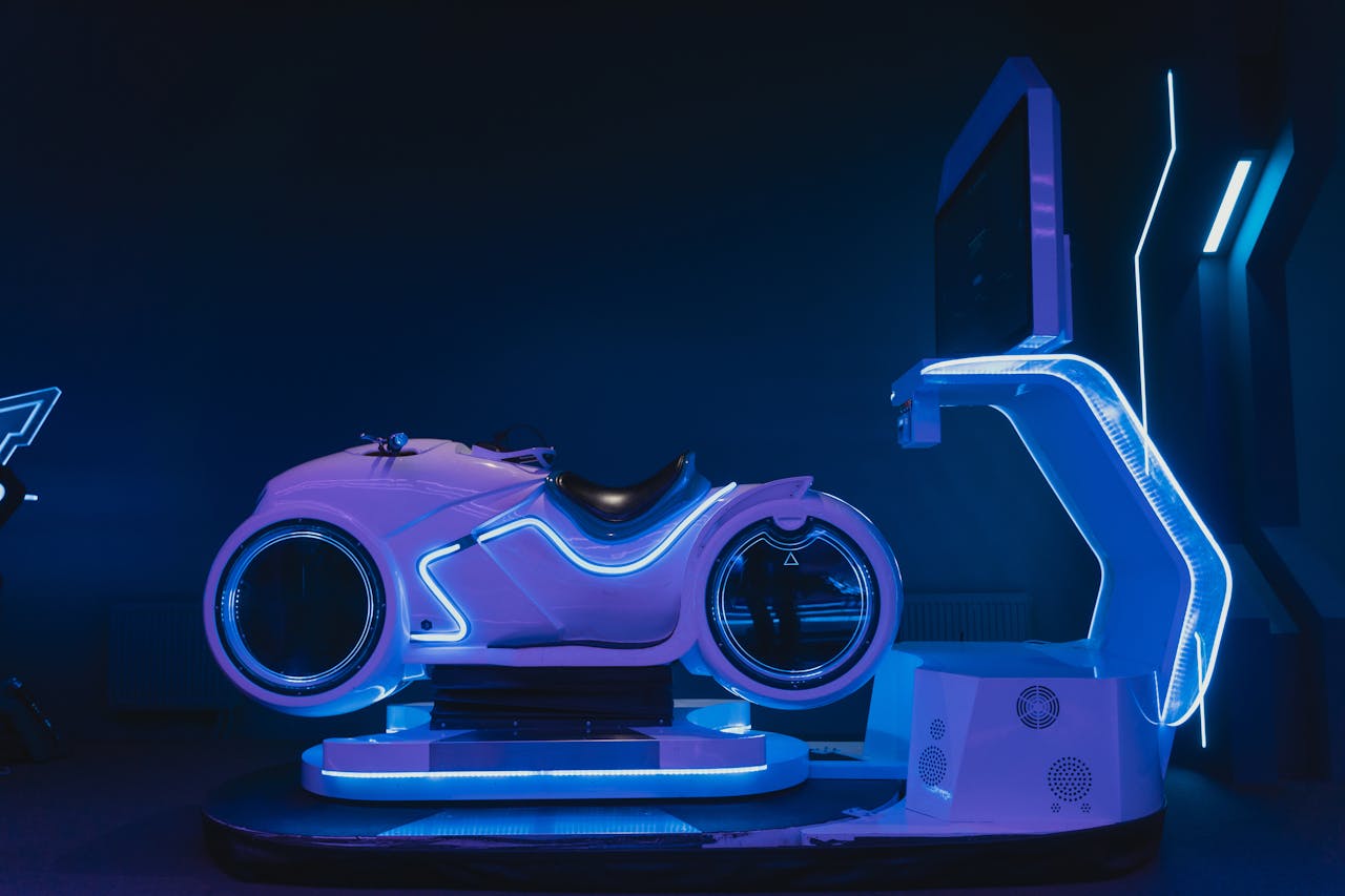 A sleek, futuristic motorbike simulator illuminated by blue neon lights in a dark indoor setting.